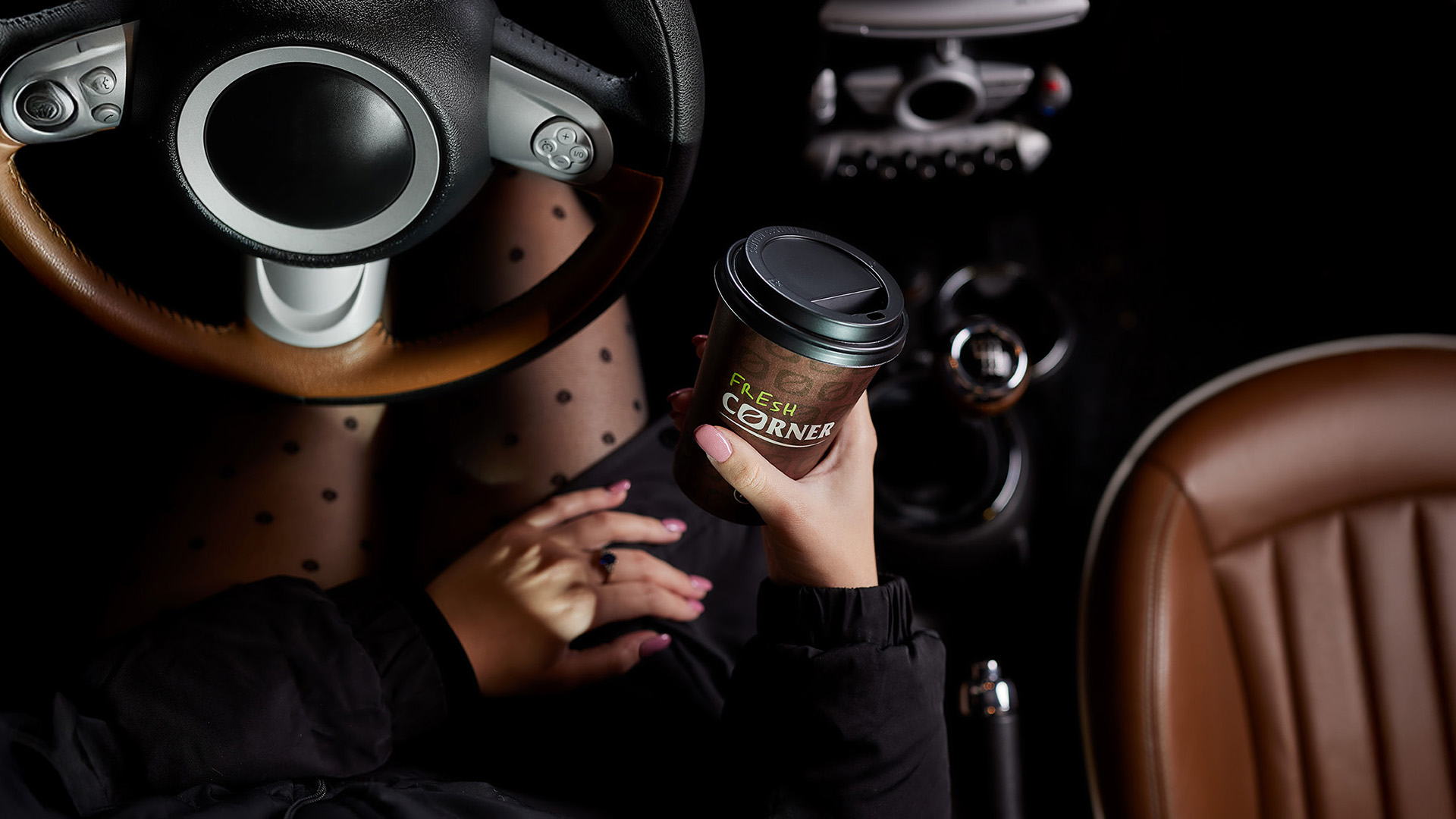 Overhead detail: a Fresh Corner coffee cup in a driver’s hand.