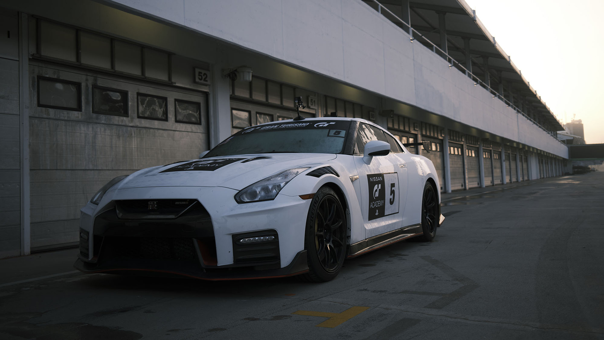 A Gran Turismo-liveried Nissan GT-R in the pit lane at dawn.